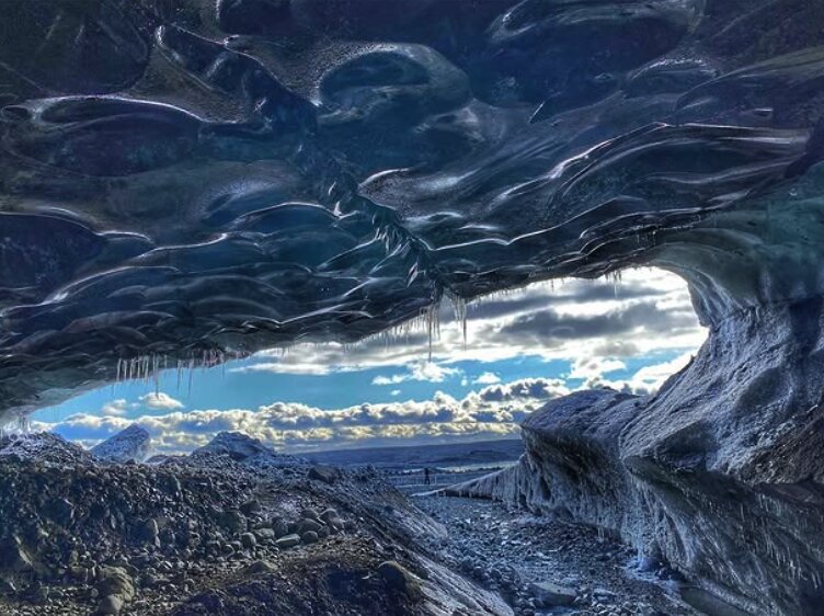 Icicles hanging from a cave mouth over an open glacial plain