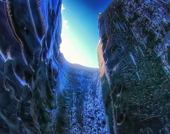 Deep blue ice walls rising to a narrow strip of sky